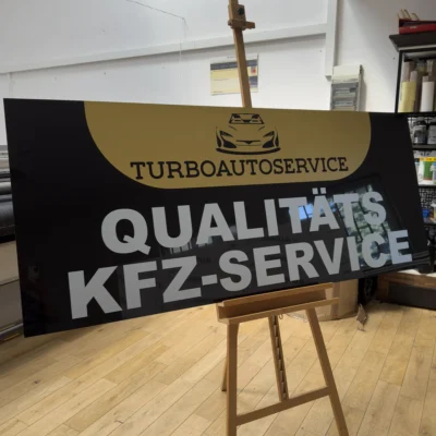 Szyld reklamowy UV na czarnym dibondzie z dużym nadrukiem literowym