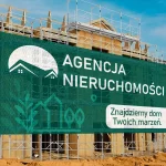 Baner mesh z reklamą agencji nieruchomości – zielony projekt z domem i hasłem promocyjnym