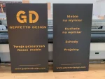 Dwie czarne tablice Geppetto Design z logo i listą usług: kuchnie, schody, projekty