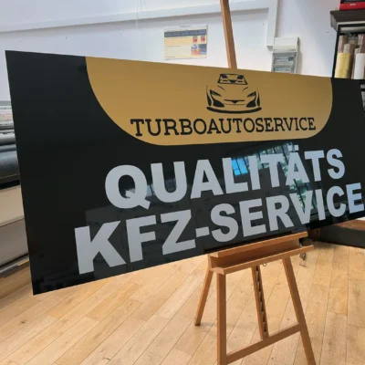 Duży szyld reklamowy z hasłem "Qualitäts KFZ-Service" nadrukowany na Dibondzie