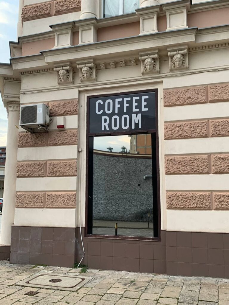 Boczny szyld reklamowy z napisem Coffee Room – czarny Dibond na oknie kawiarni