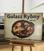 Schild mit dem Gericht „Fischgulasch”, Grafik einer Fischsuppe auf Plexiglasplatte