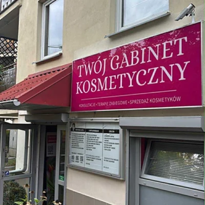 Szyld reklamowy Twój Gabinet Kosmetyczny w kolorze różowym na elewacji budynku