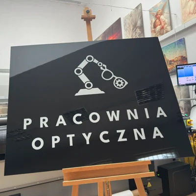 Czarna tablica Pracownia Optyczna z symbolem robota, tablice i szyldy reklamowe