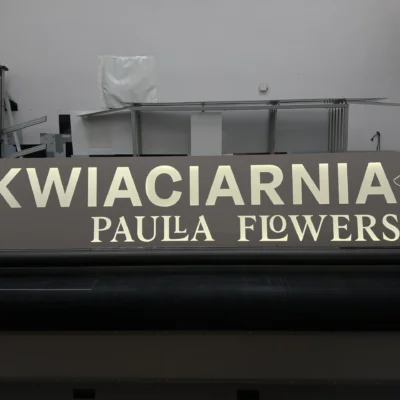 Panoramiczny szyld reklamowy z nadrukiem UV, duże litery i grafika na ciemnym tle