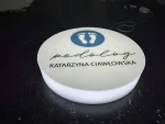 Podświetlany kaseton okrągły z plexi: podolog Katarzyna Ciawłowska, logo stóp, druk UV