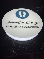 Zbliżenie kasetonu LED z plexi z napisem „podolog” i nazwiskiem, precyzyjny druk UV