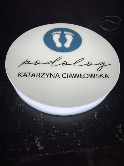 Zbliżenie kasetonu LED z plexi z napisem „podolog” i nazwiskiem, precyzyjny druk UV