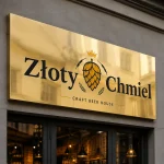 Złoty lustrzany szyld z zaginanym bokiem na fasadzie pubu