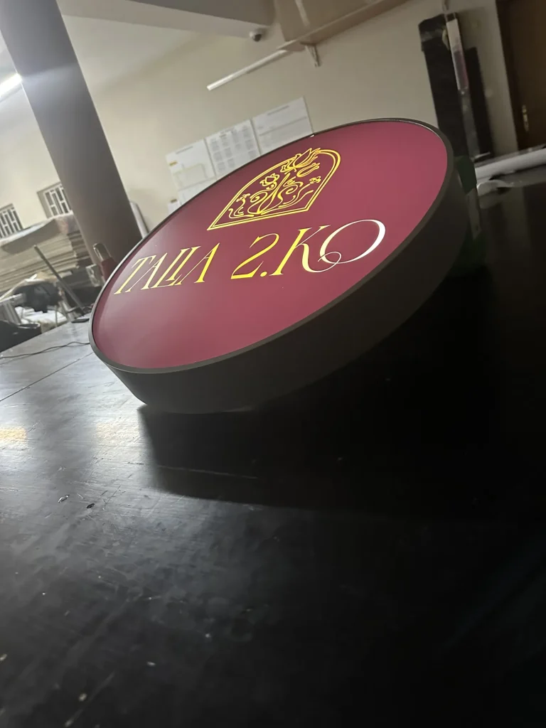 Kaseton reklamowy okrągły z bordowym frontem i złotym logo