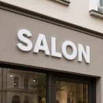 Białe litery z PCV zamontowane na elewacji nad wejściem do salonu