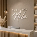 Napis z mlecznej plexi zamontowany na ścianie recepcji studia urody