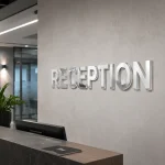 Srebrny lustrzany napis przestrzenny z plexi za ladą recepcyjną