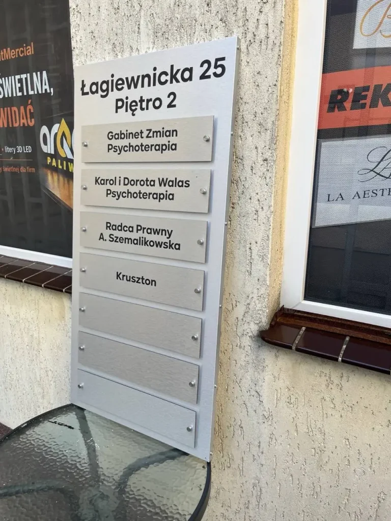 Wysoka tablica zbiorcza Dibond ustawiona obok wejścia