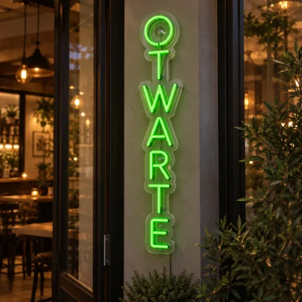 Zielony neon LED z pionowym napisem OTWARTE przy wejściu do lokalu